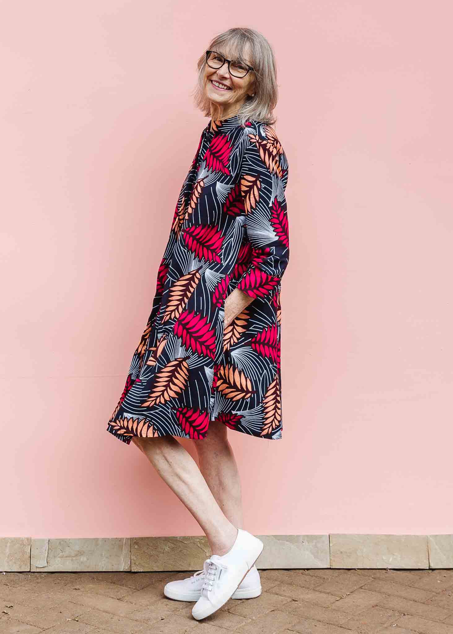 Model wearing a navy dress with red and peach feather print.