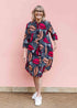 Model wearing a navy dress with red and peach feather print.