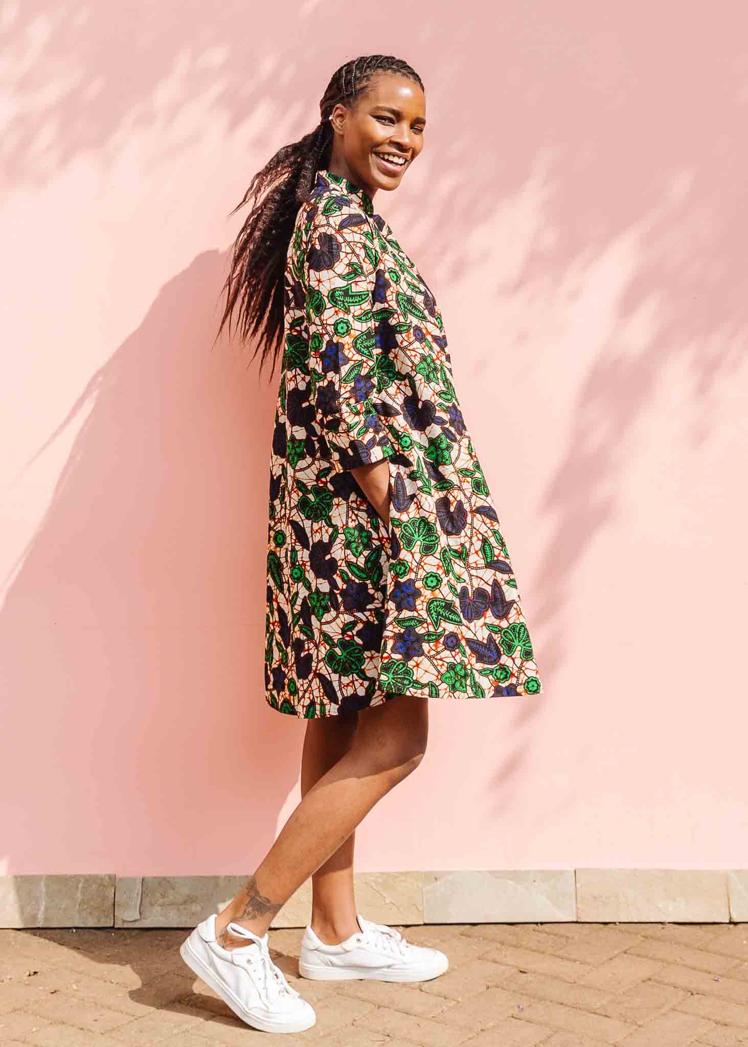 Model wearing brown dress with green and blue vine print.