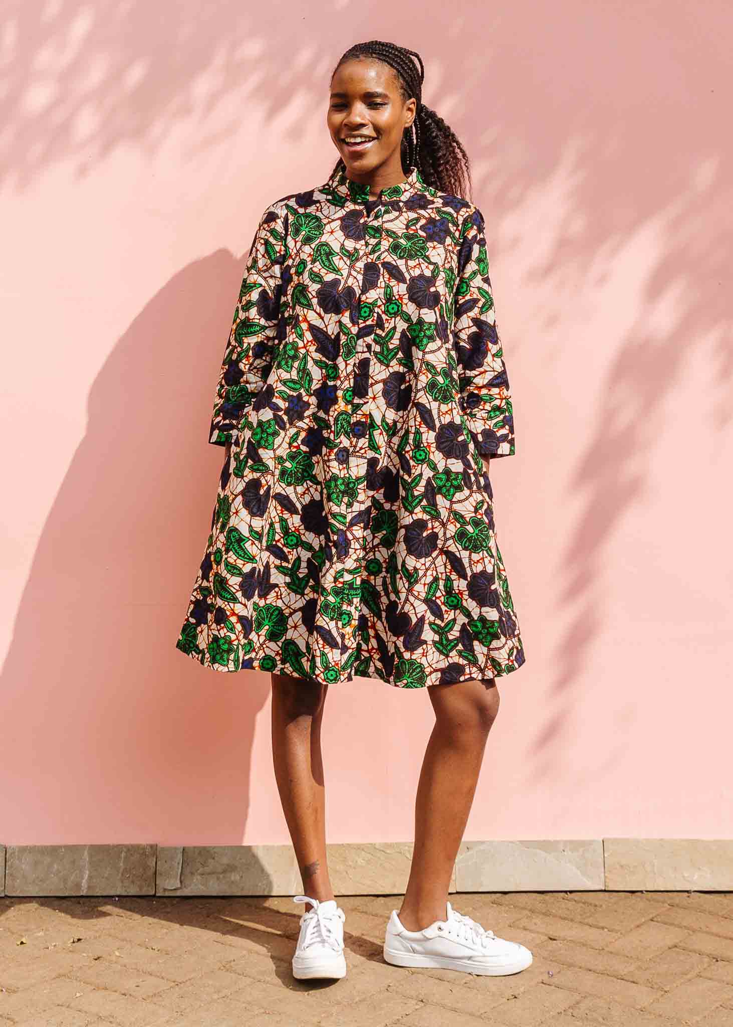 Model wearing brown dress with green and blue vine print.