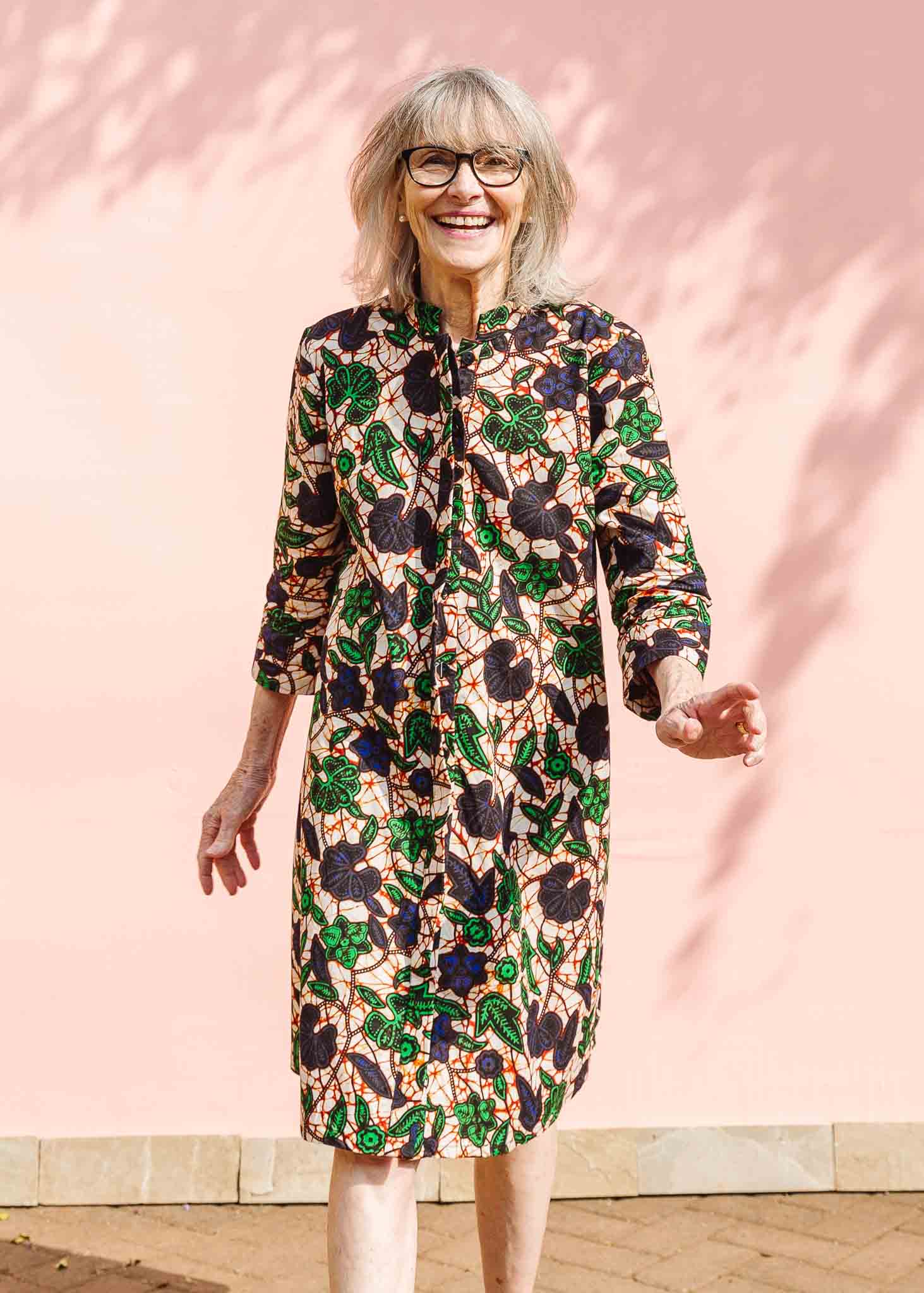 Model wearing brown dress with green and blue vine print.