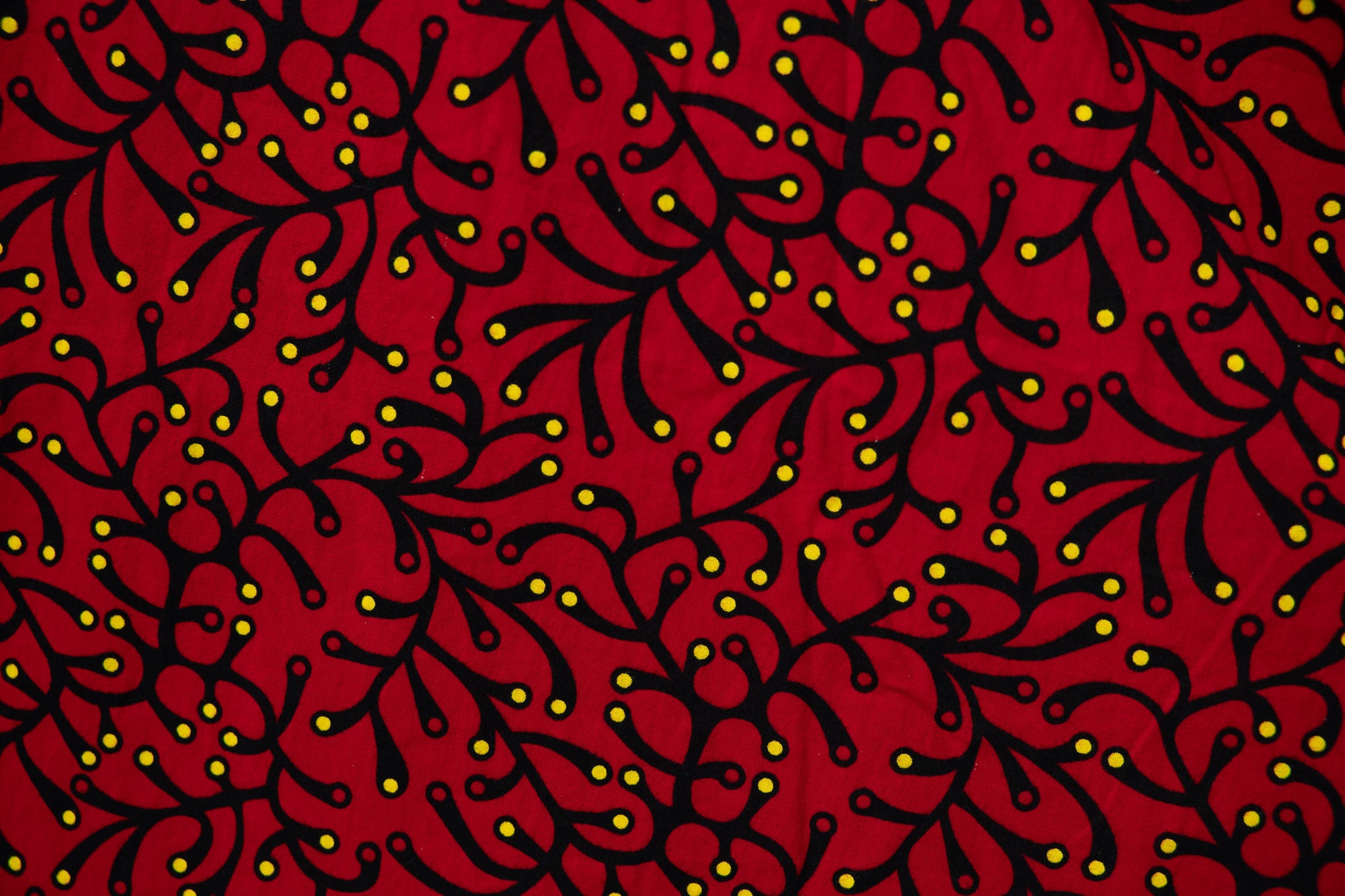 Close up display of red dress with small black and yellow branch design.