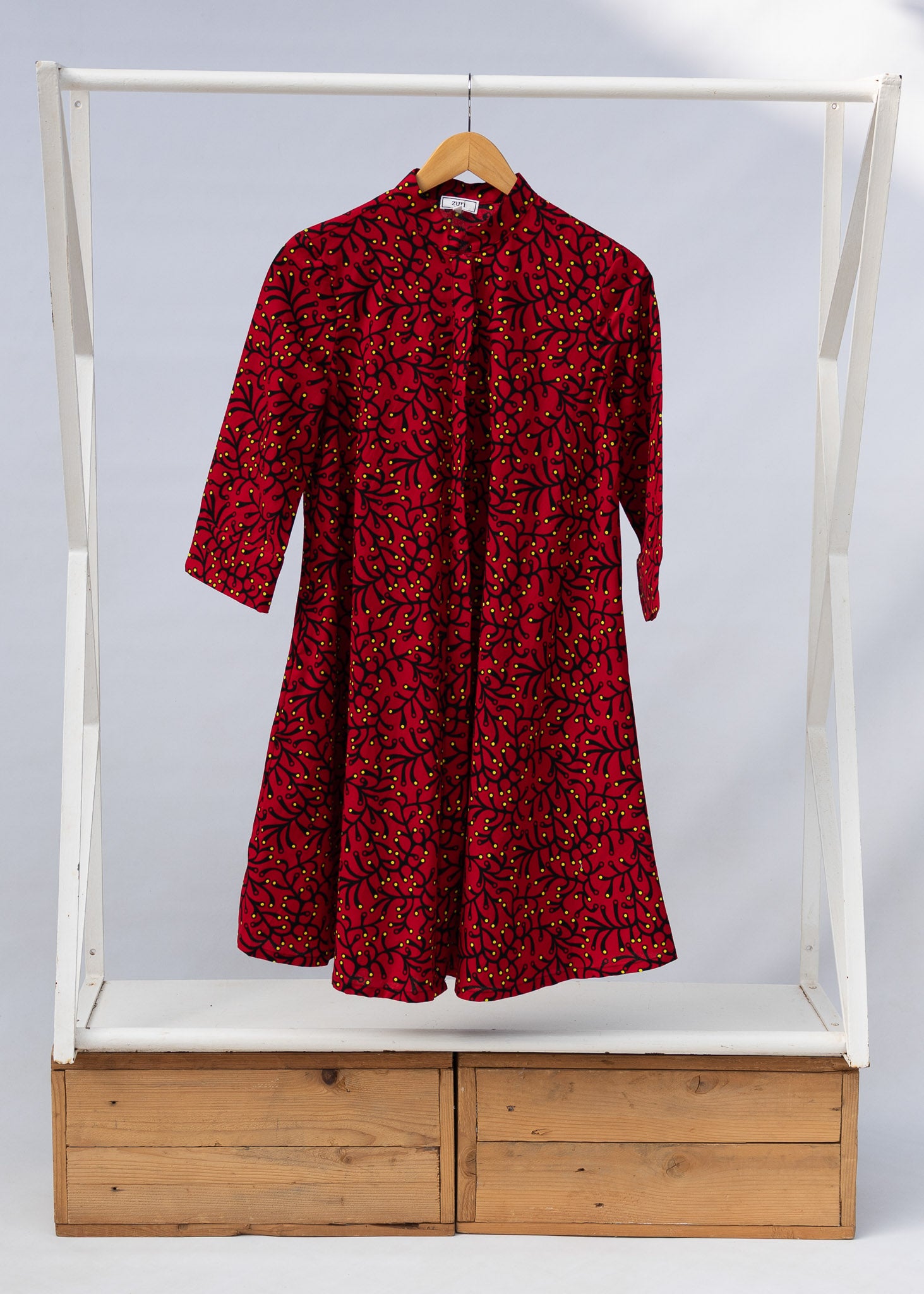 Display of red dress with small black and yellow branch design.