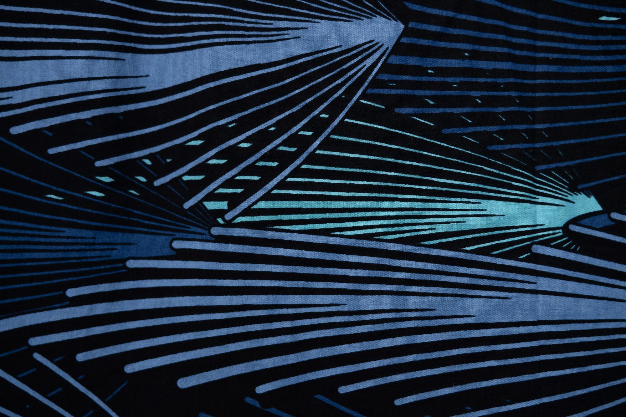 Close up display of black dress with aqua and navy abstract print, fabric.