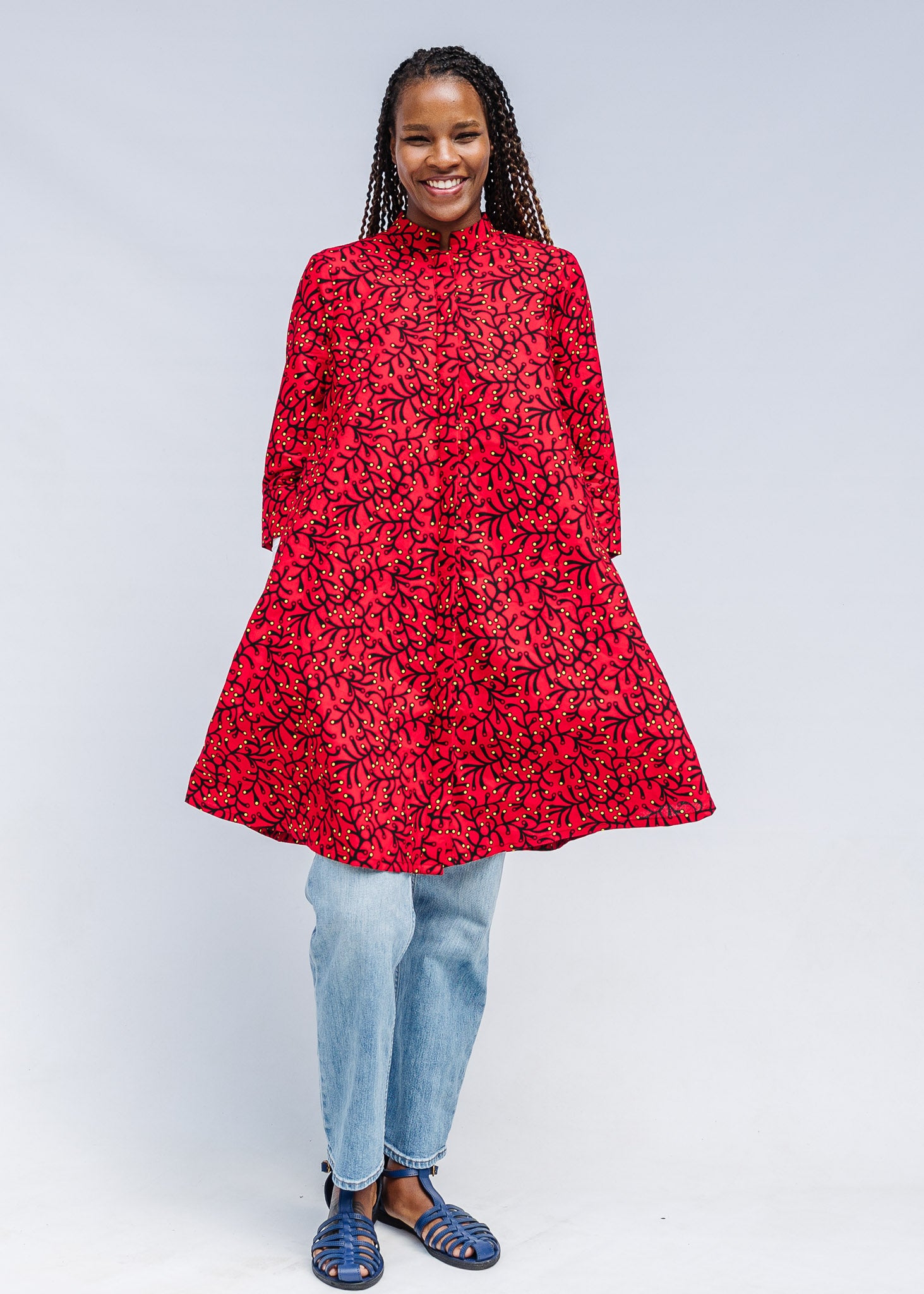 Model wearing red dress with small black and yellow branch design.