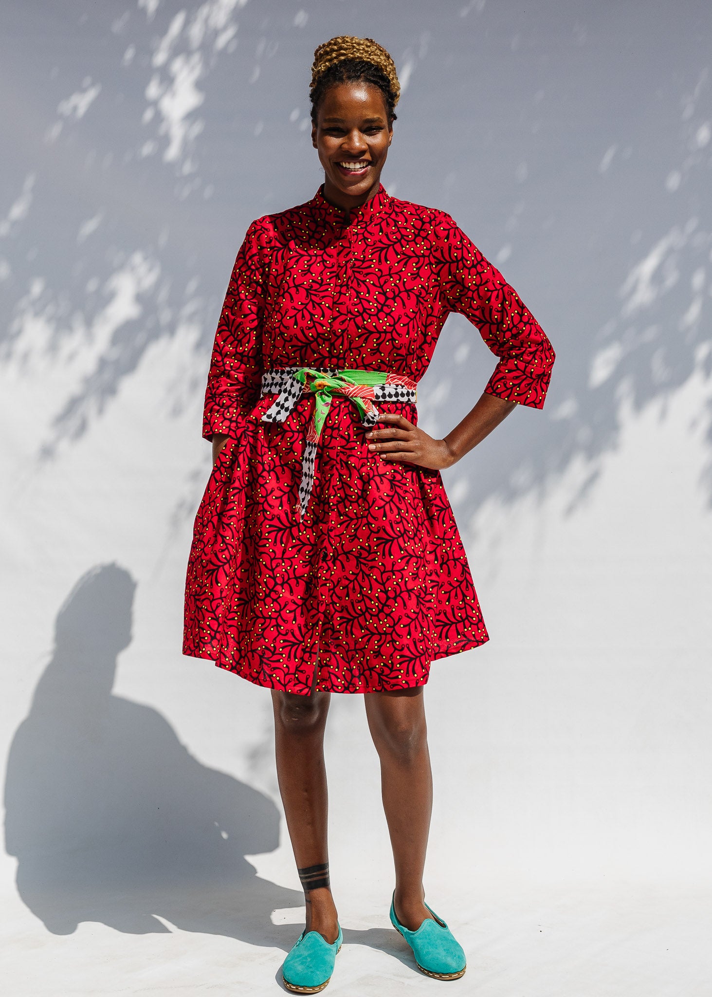 Model wearing red dress with small black and yellow branch design.