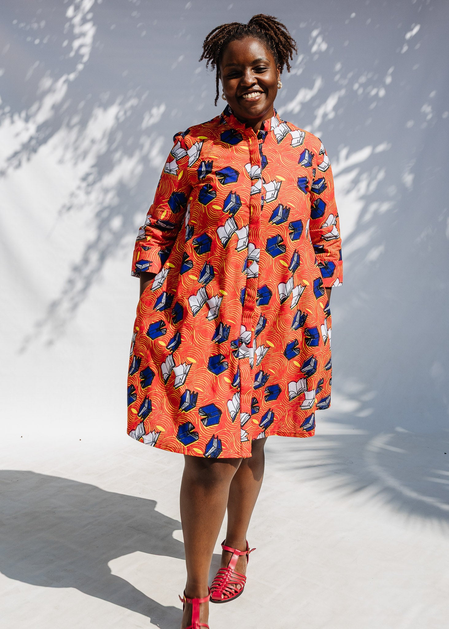 Model wearing yellow and red, blue book print dress.