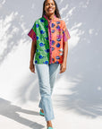 Model wearing green, orange and pink multiprint shirt.