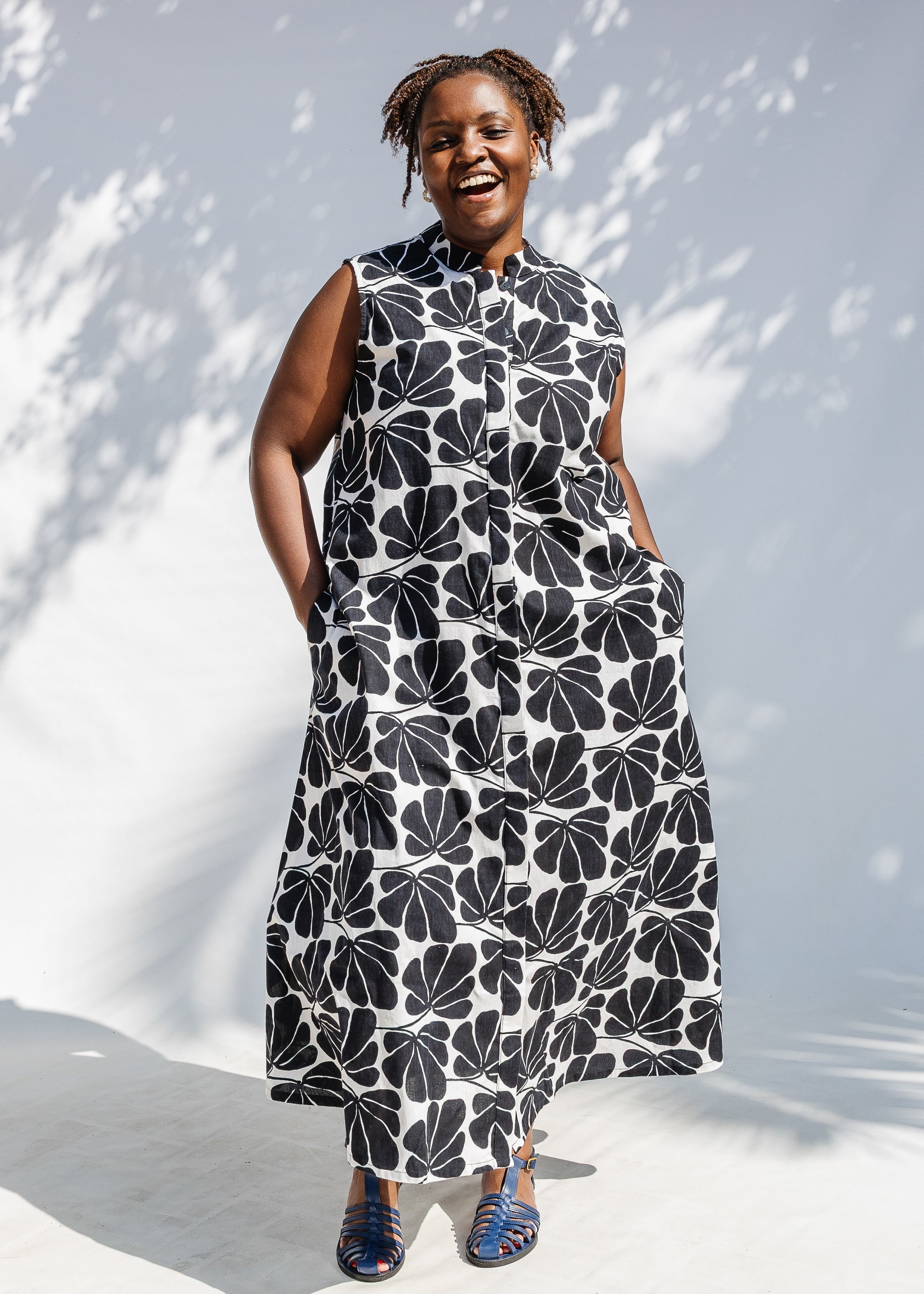 Model wearing black and white floral print, sleeveless dress.