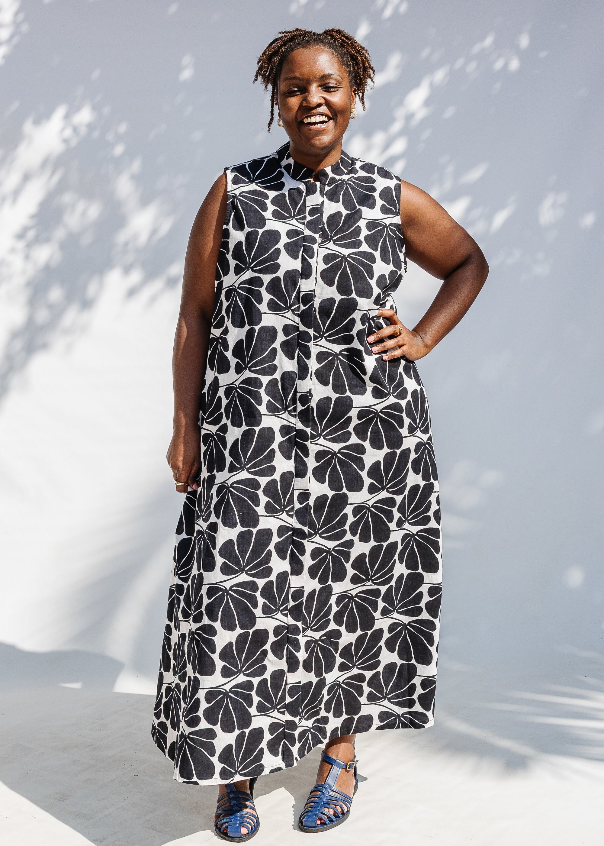 Model wearing black and white floral print, sleeveless dress.