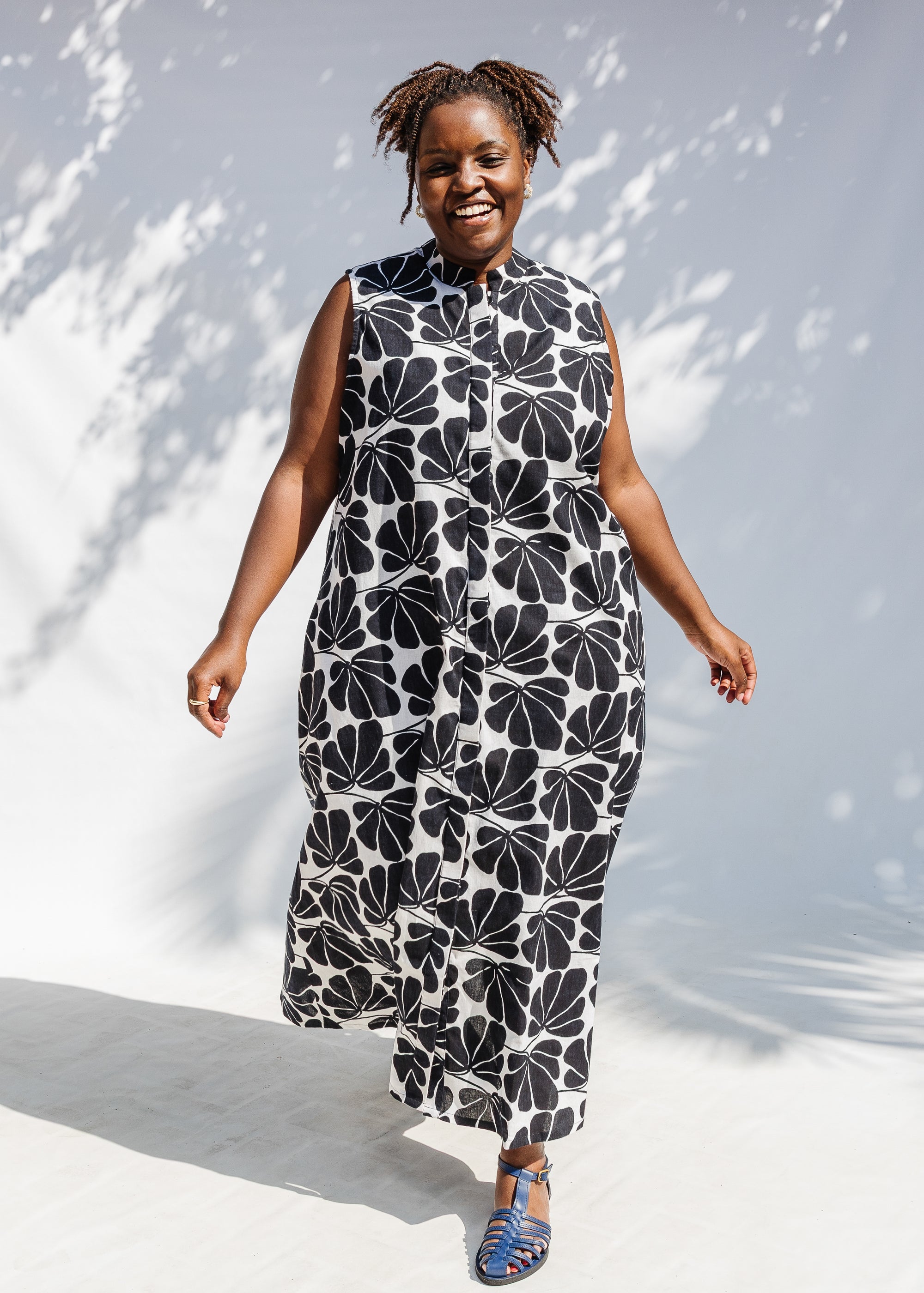 Model wearing black and white floral print, sleeveless dress.