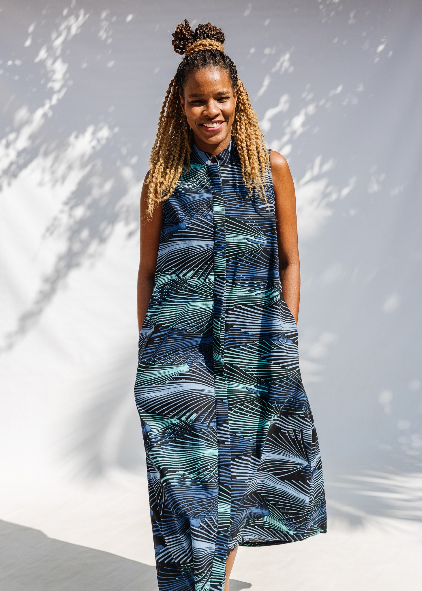 Model wearing black dress with aqua and navy abstract print.