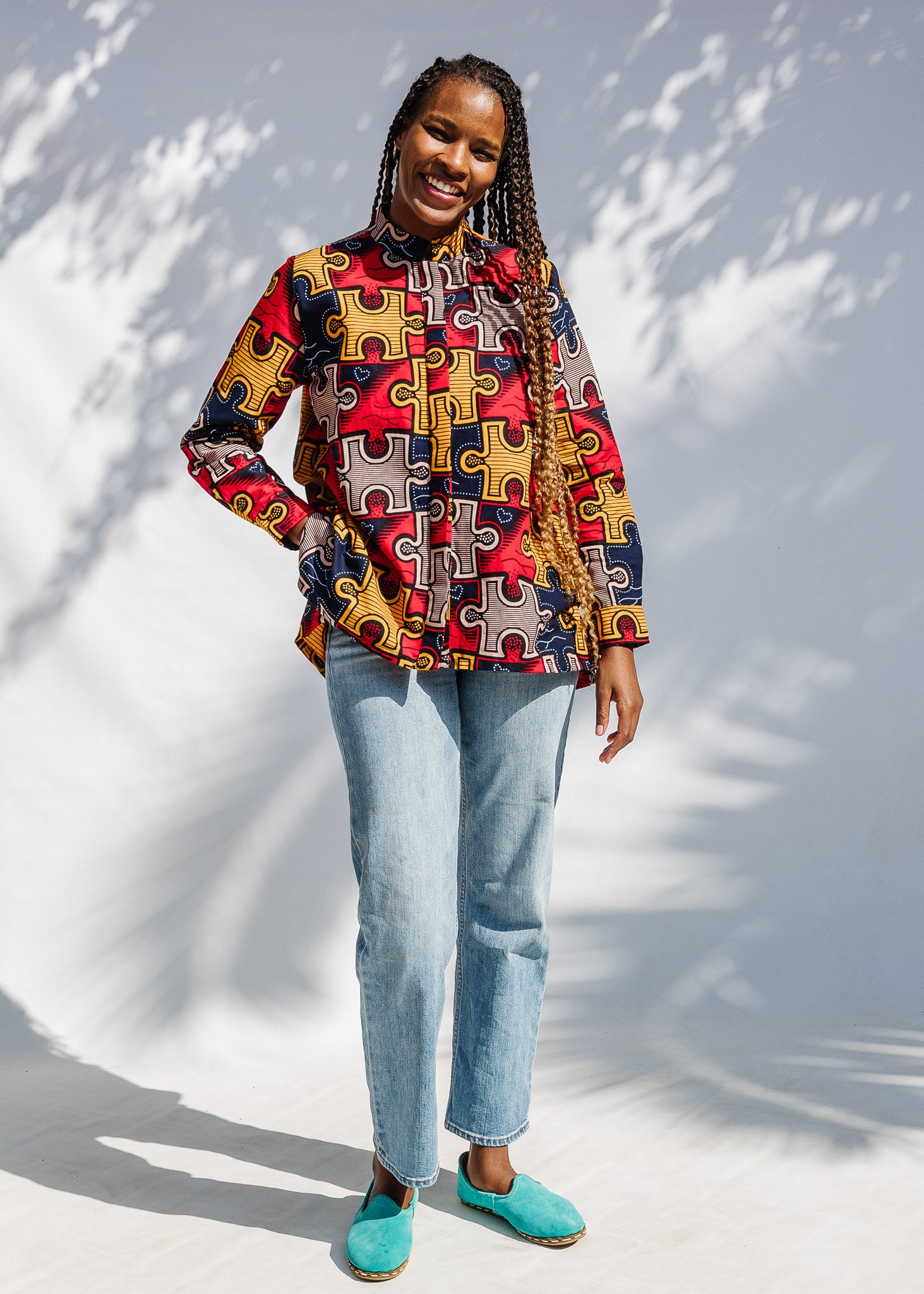 Model wearing multicolored puzzle print shirt.