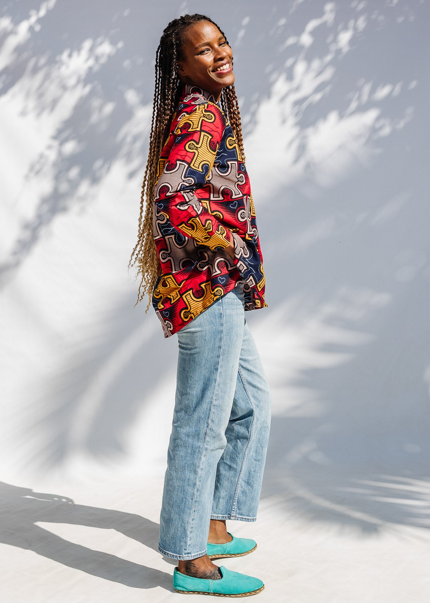 Model wearing multicolored puzzle print shirt.