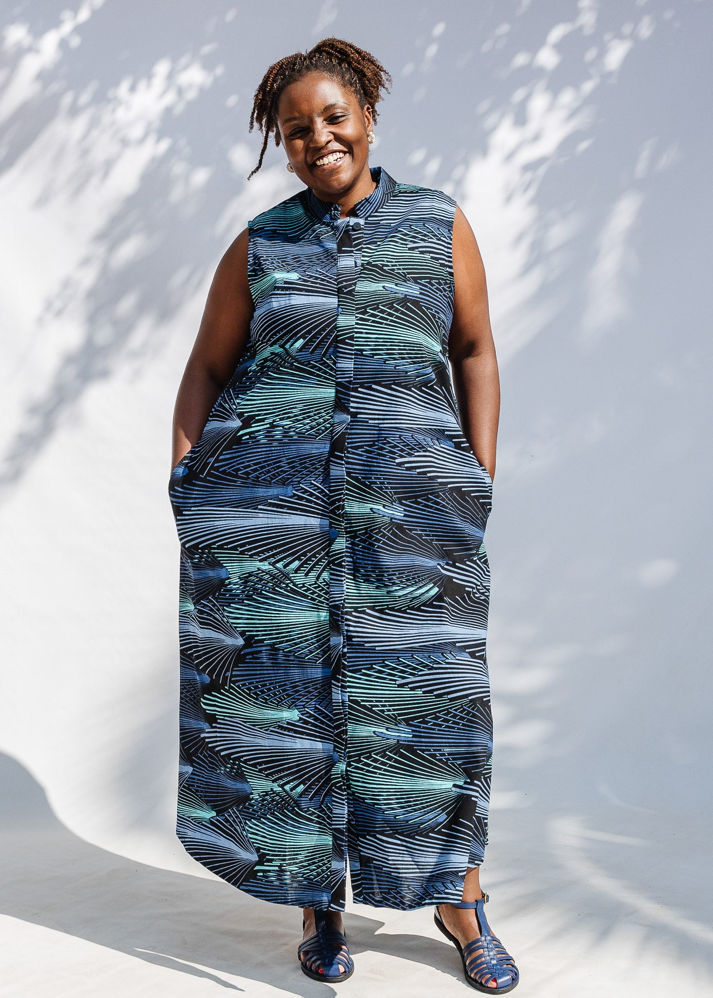 Model wearing black dress with aqua and navy abstract print.
