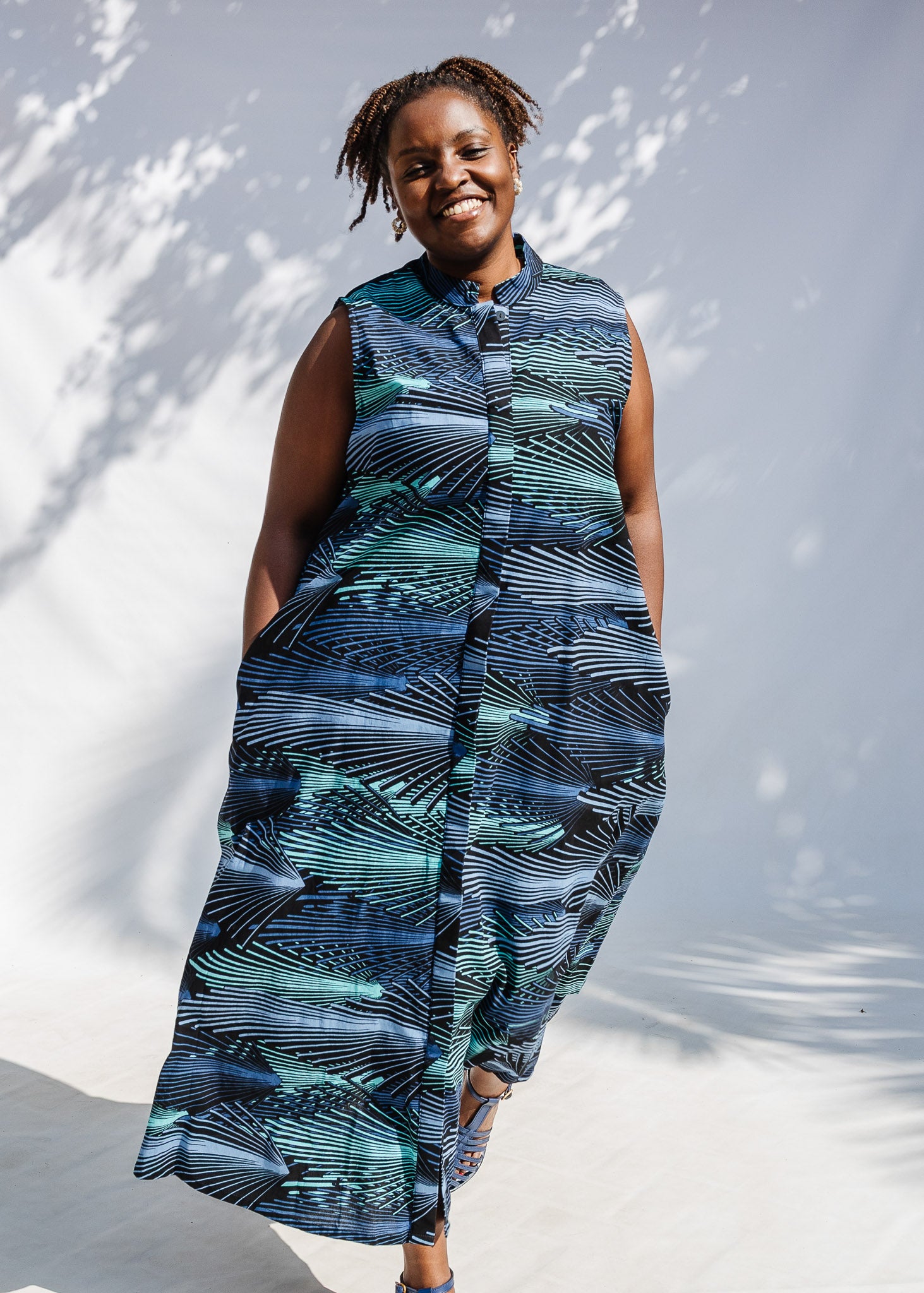 Model wearing black dress with aqua and navy abstract print.