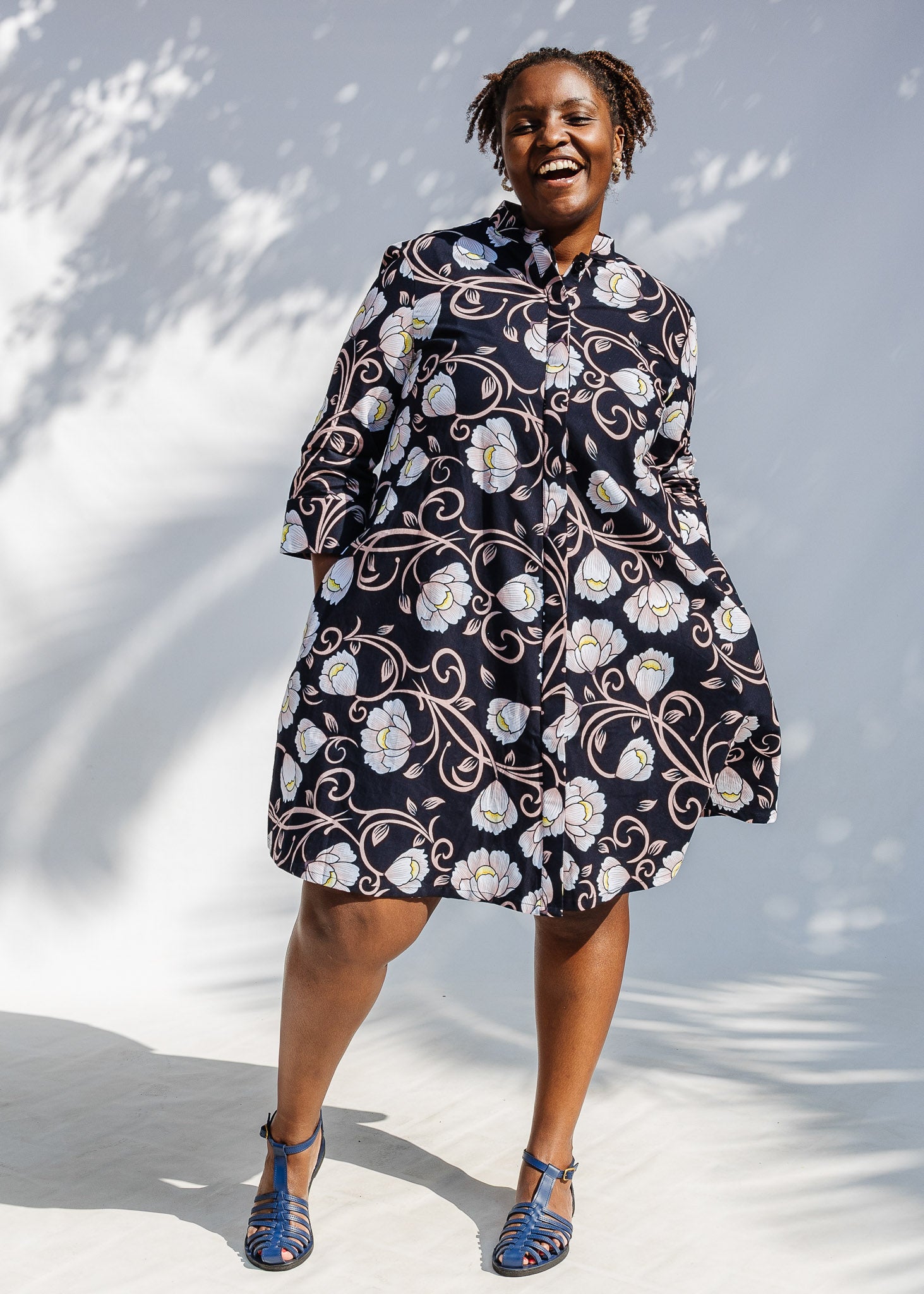 Model wearing black dress with pink and yellow floral print.