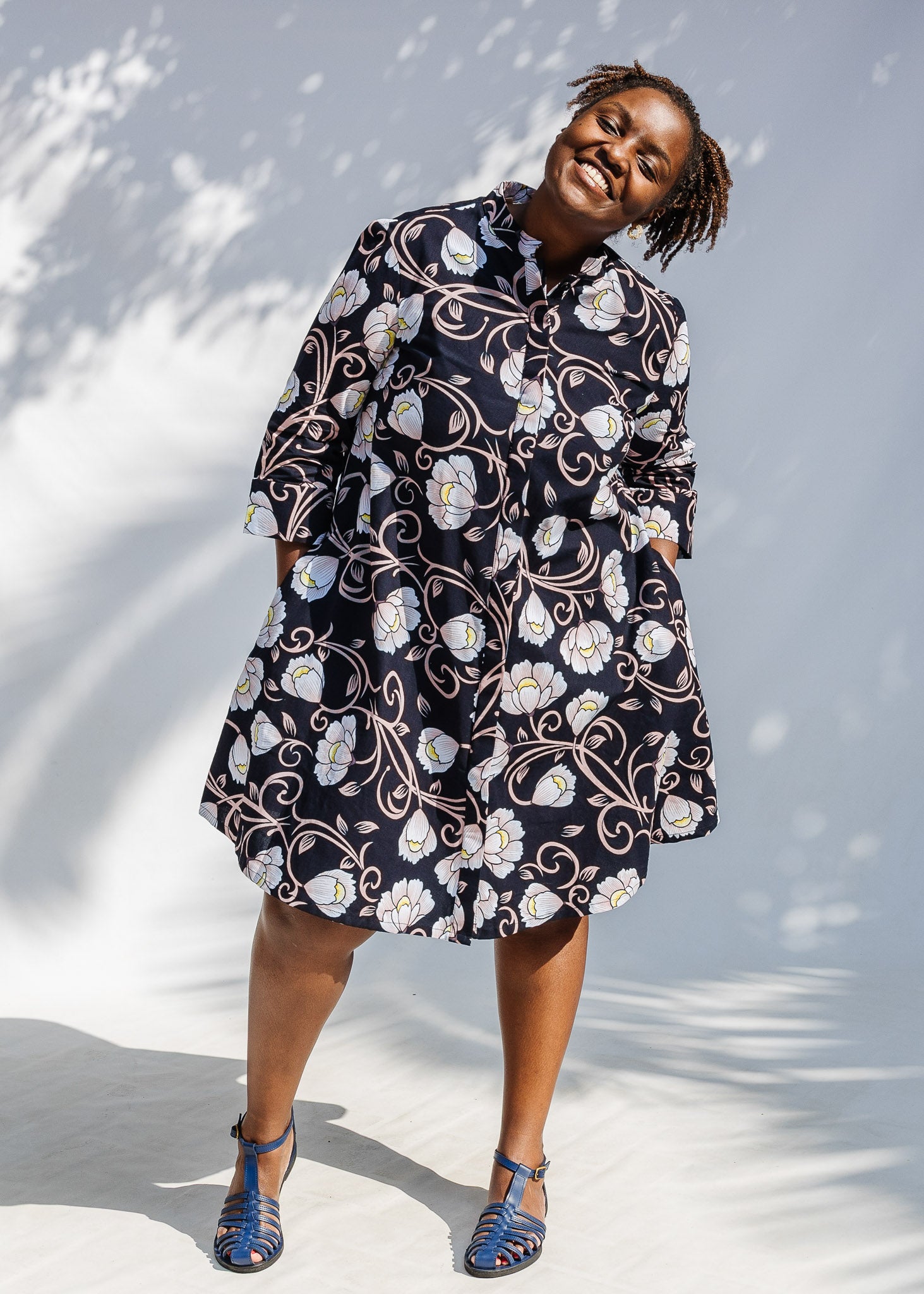 Model wearing black dress with pink and yellow floral print.