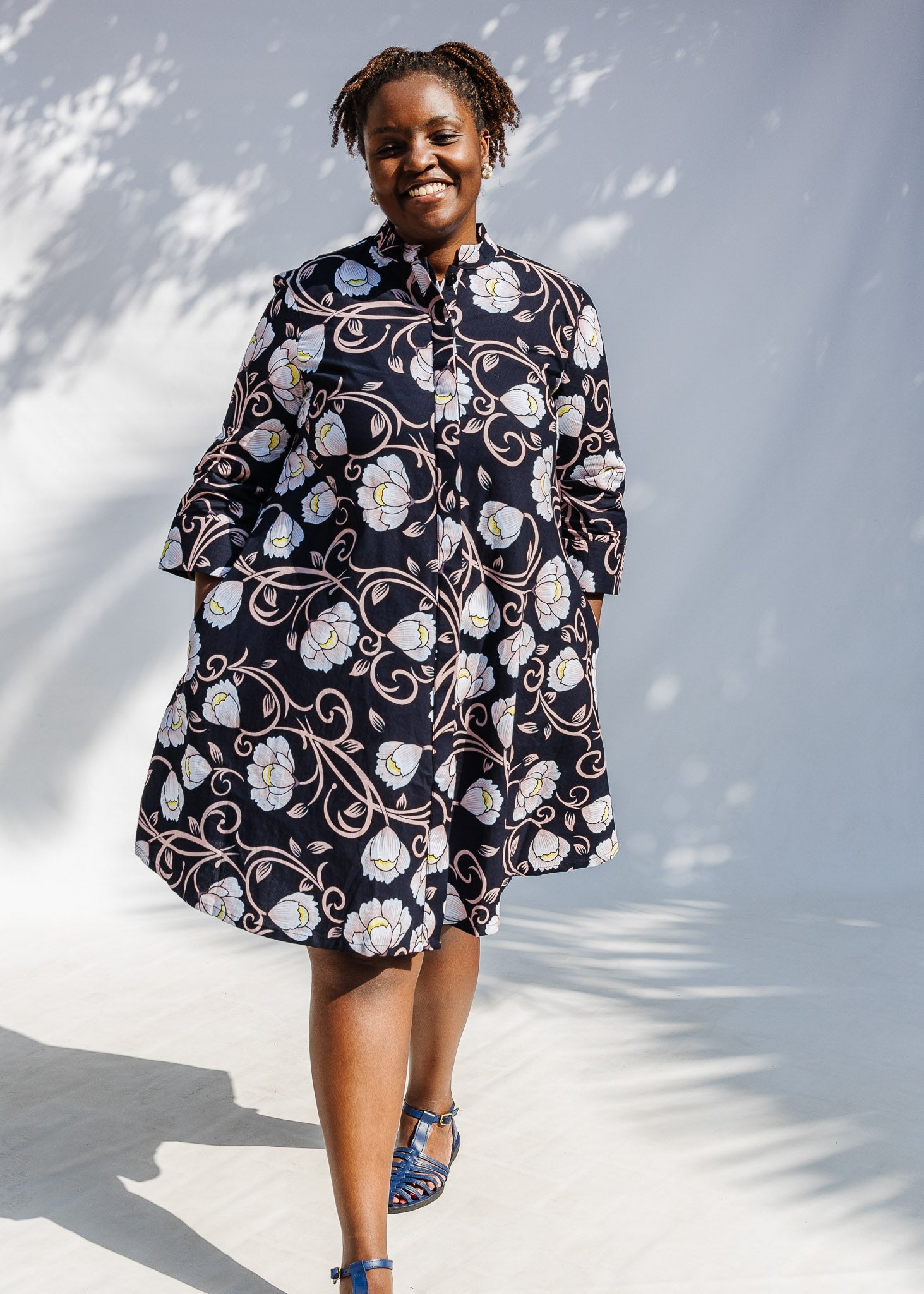 Model wearing black dress with pink and yellow floral print.
