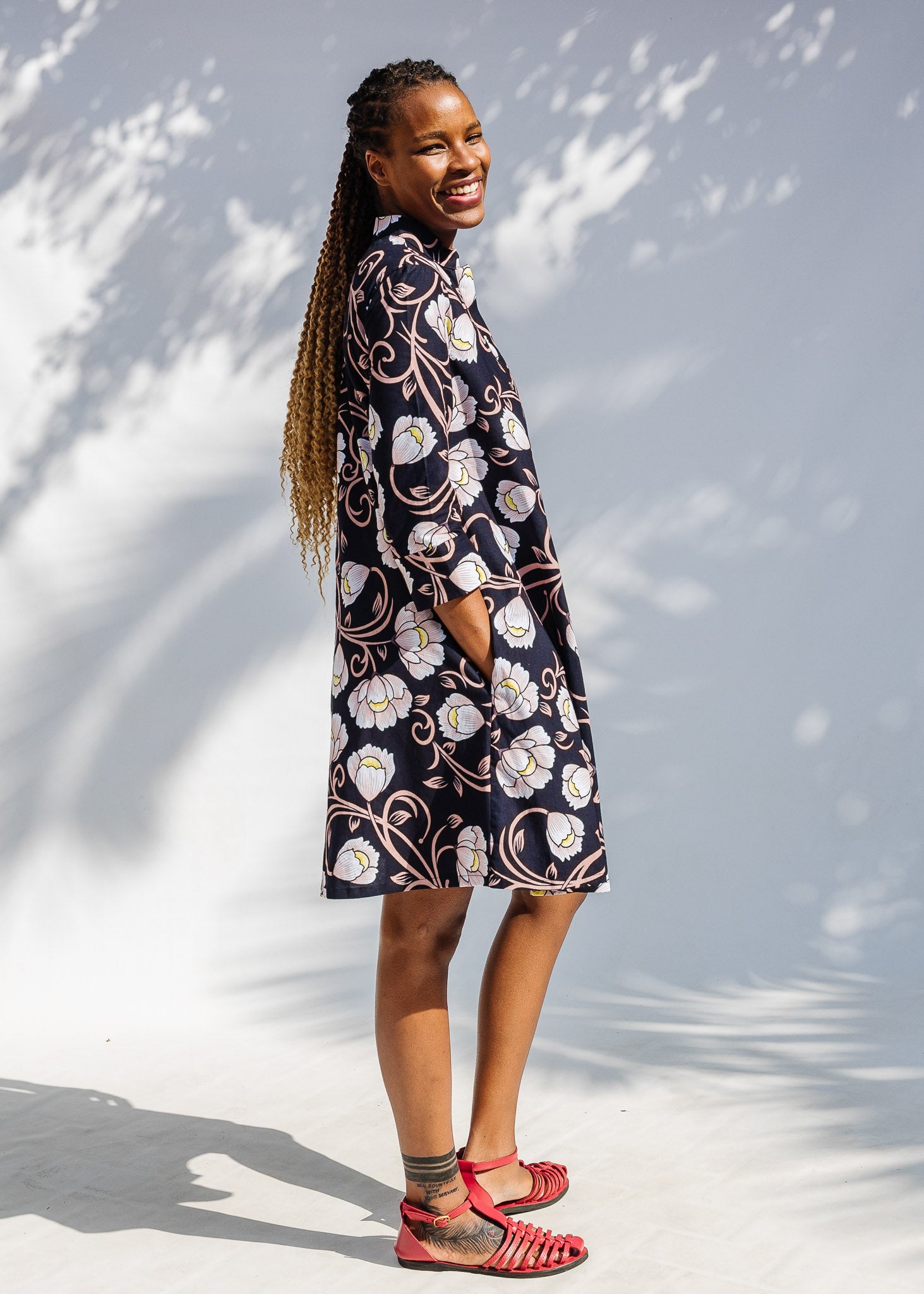 Model wearing black dress with pink and yellow floral print.