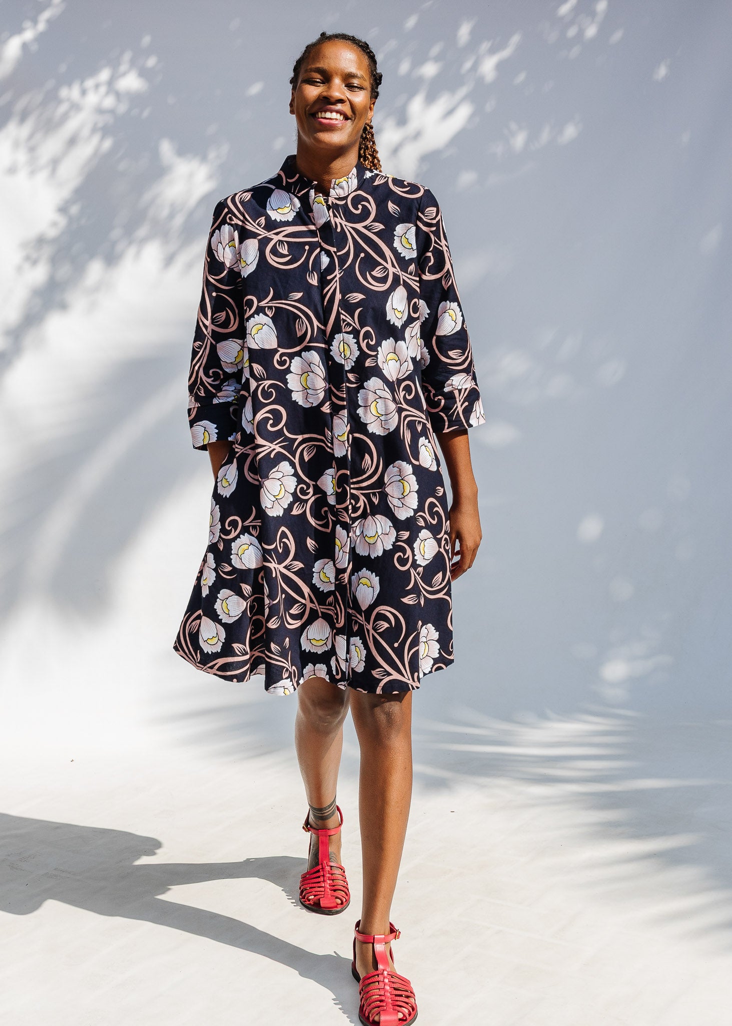 Model wearing black dress with pink and yellow floral print.