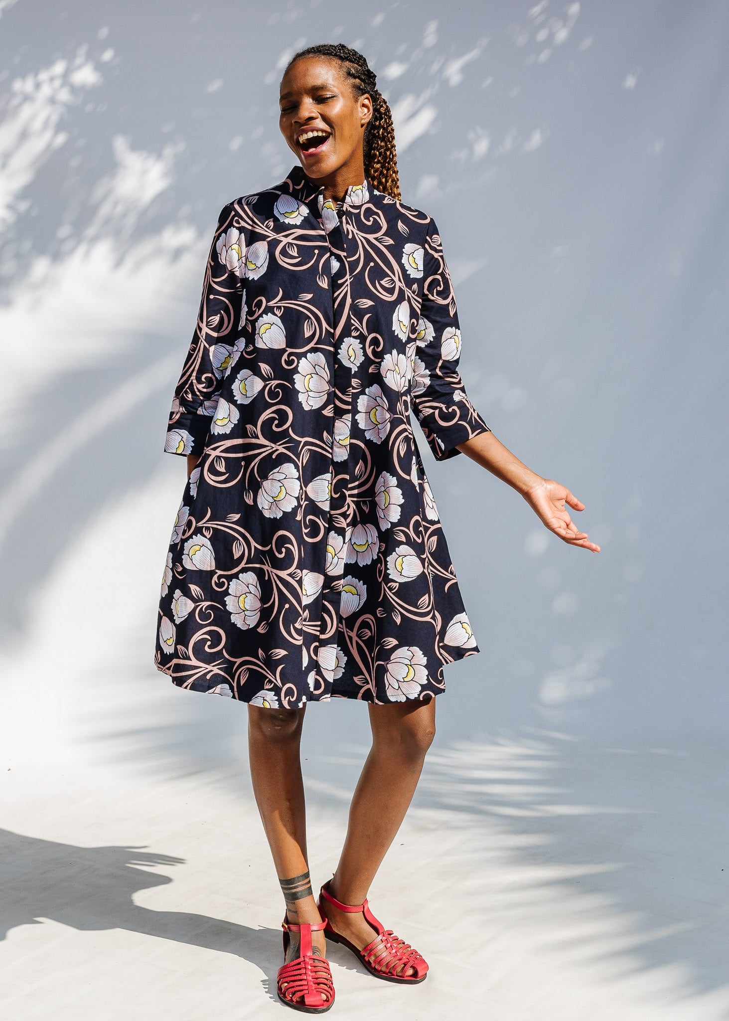 Model wearing black dress with pink and yellow floral print.