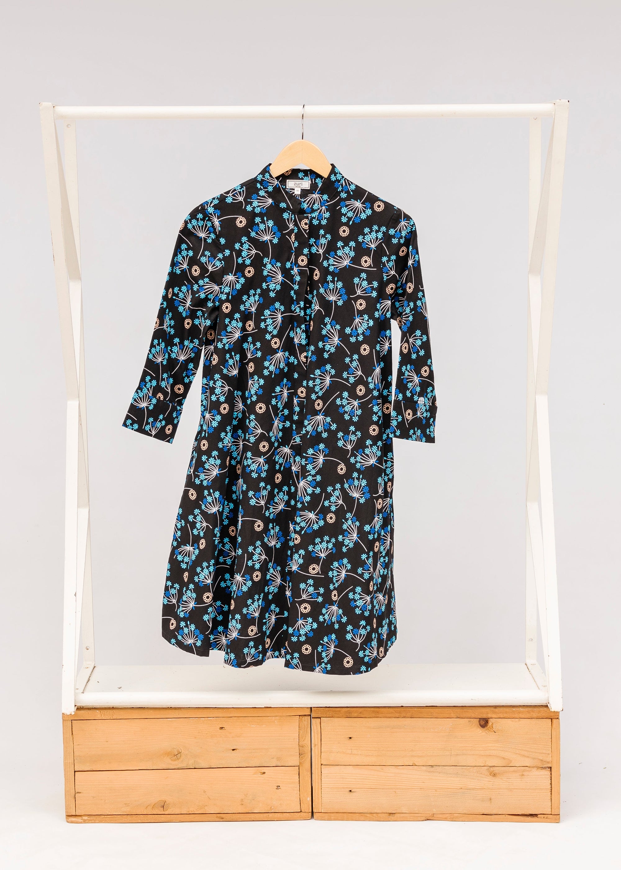 Display of black dress with blue and beige floral print.