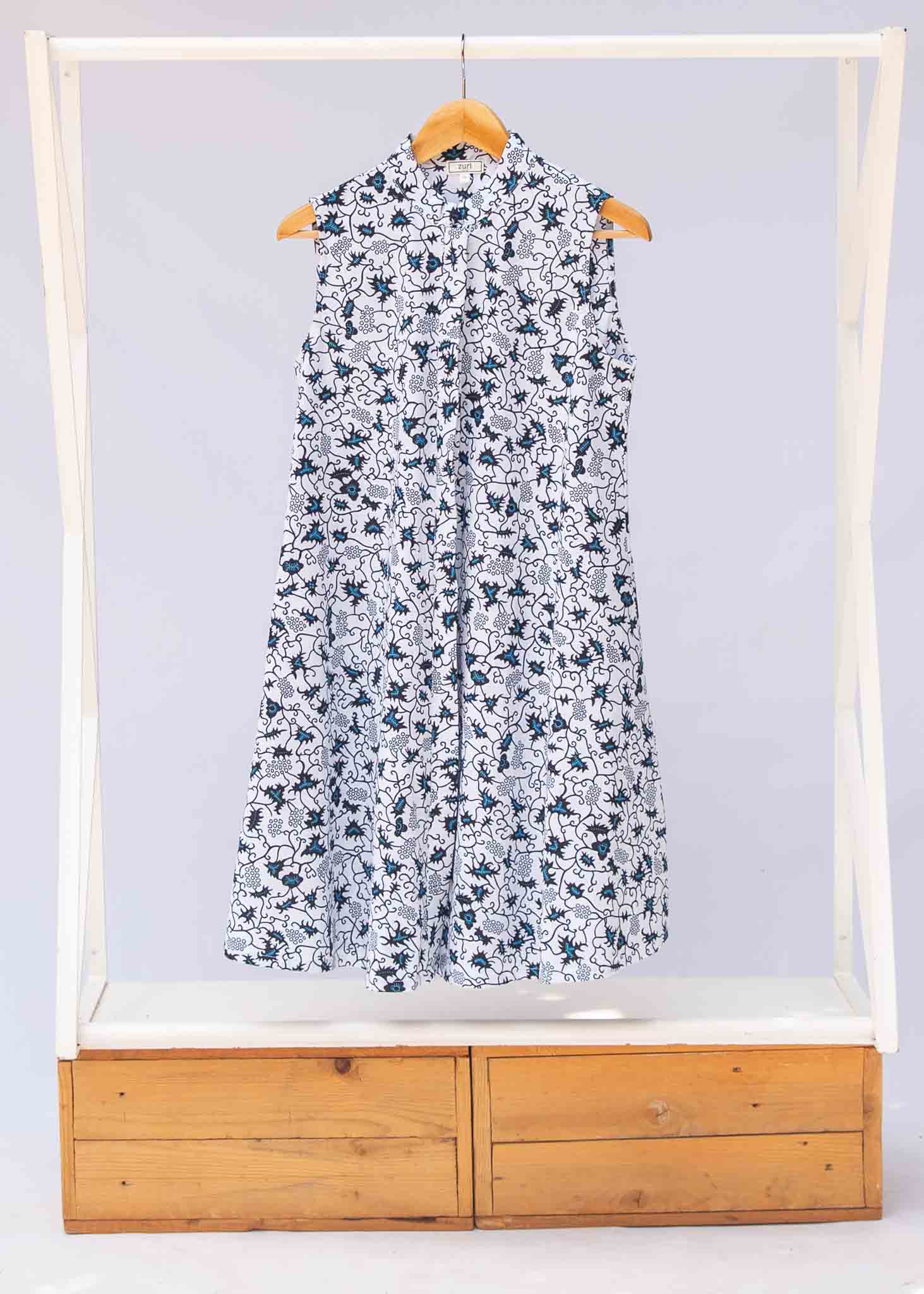 Display of white sleeveless dress with blue floral print.