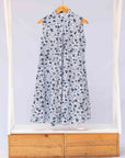 Display of white sleeveless dress with blue floral print.