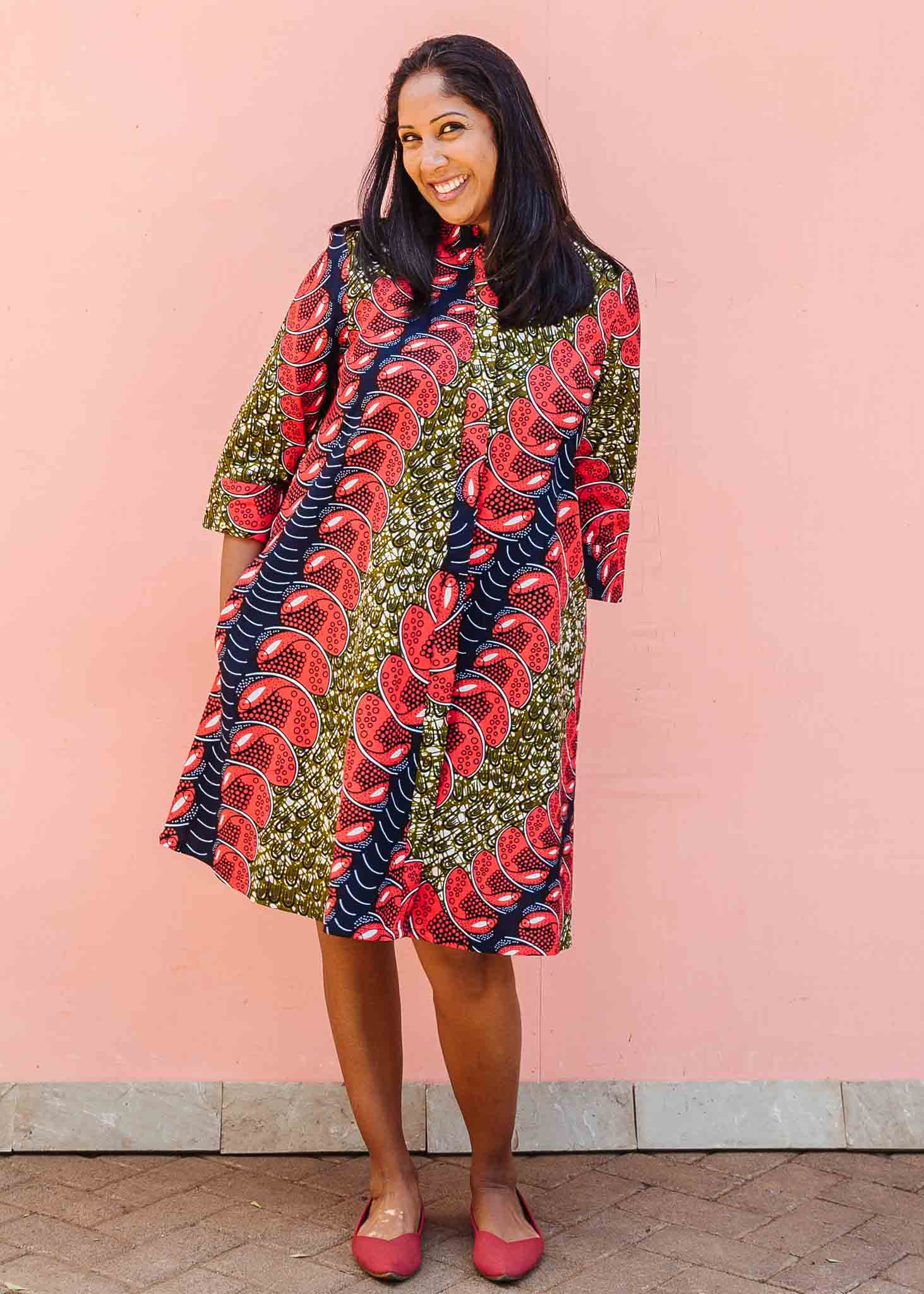 Model wearing green dress, with bold red and navy fish print.