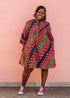 Model wearing green dress, with bold red and navy fish print.