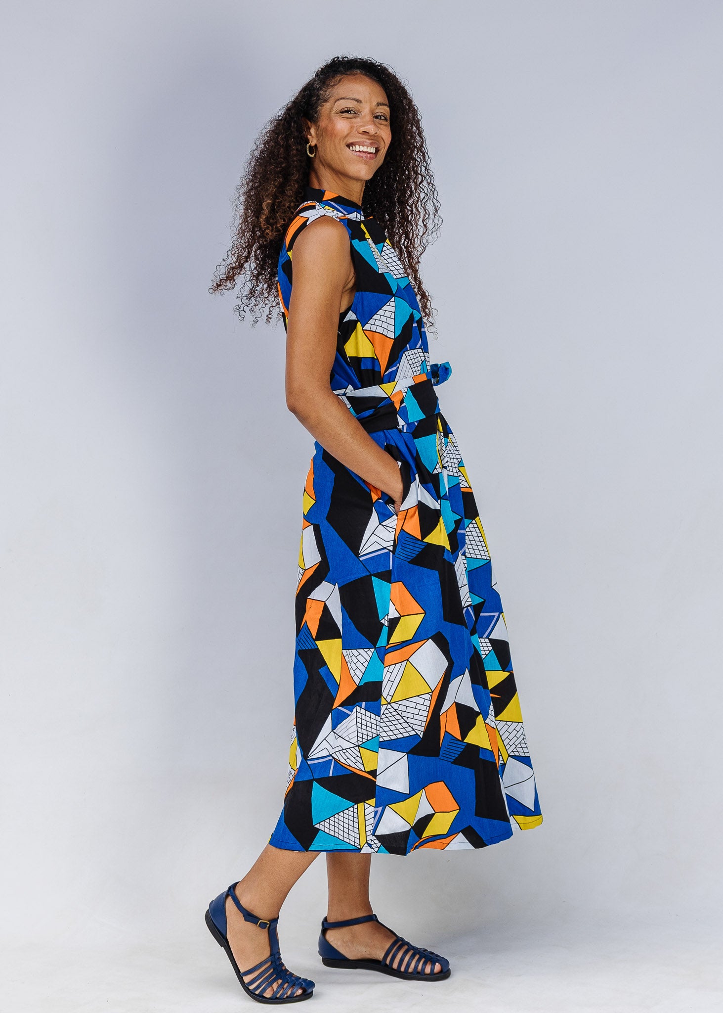 Model wearing blue dress with yellow, black, orange and white geometric print.