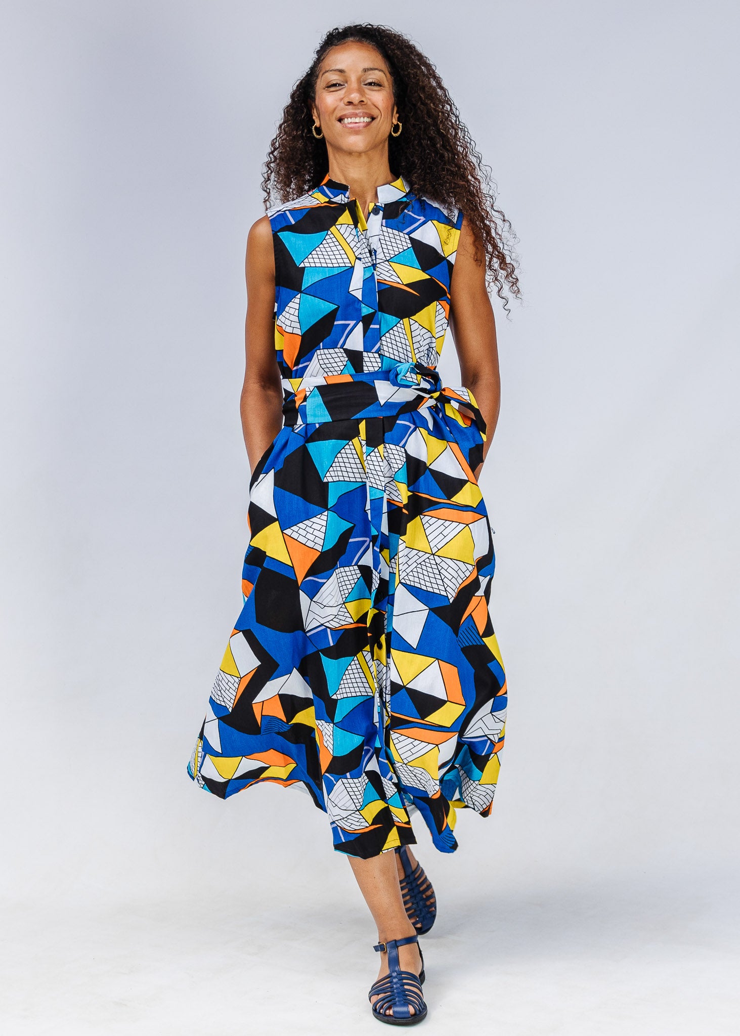 Model wearing blue dress with yellow, black, orange and white geometric print.