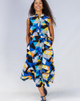 Model wearing blue dress with yellow, black, orange and white geometric print.
