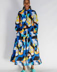 Model wearing blue, black, orange, yellow and white geometric print shirt and pant set.