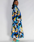 Model wearing blue, black, orange, yellow and white geometric print shirt and pant set.
