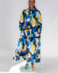 Model wearing blue, black, orange, yellow and white geometric print shirt and pant set.