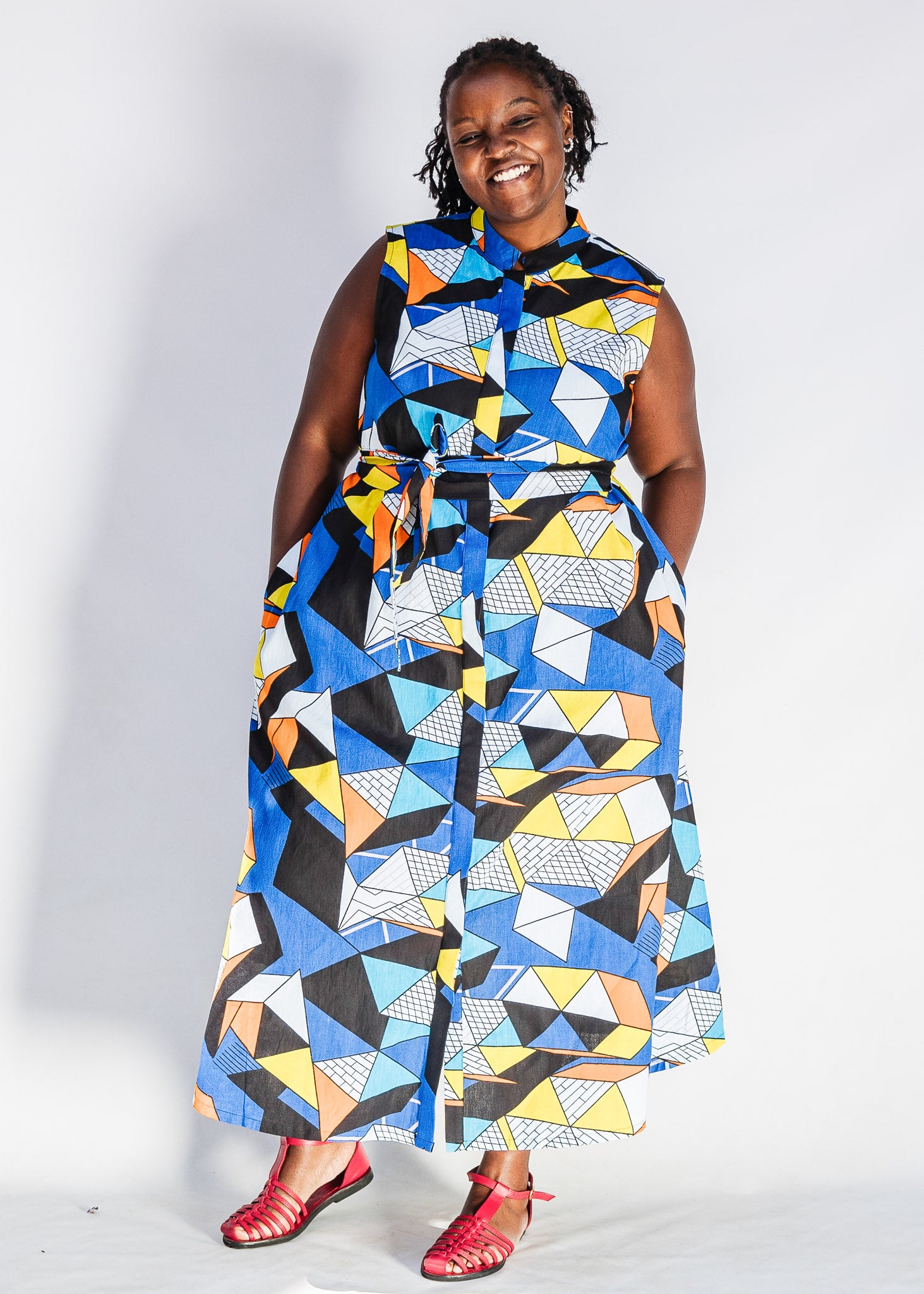 Model wearing blue dress with yellow, black, orange and white geometric print.