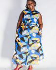 Model wearing blue dress with yellow, black, orange and white geometric print.