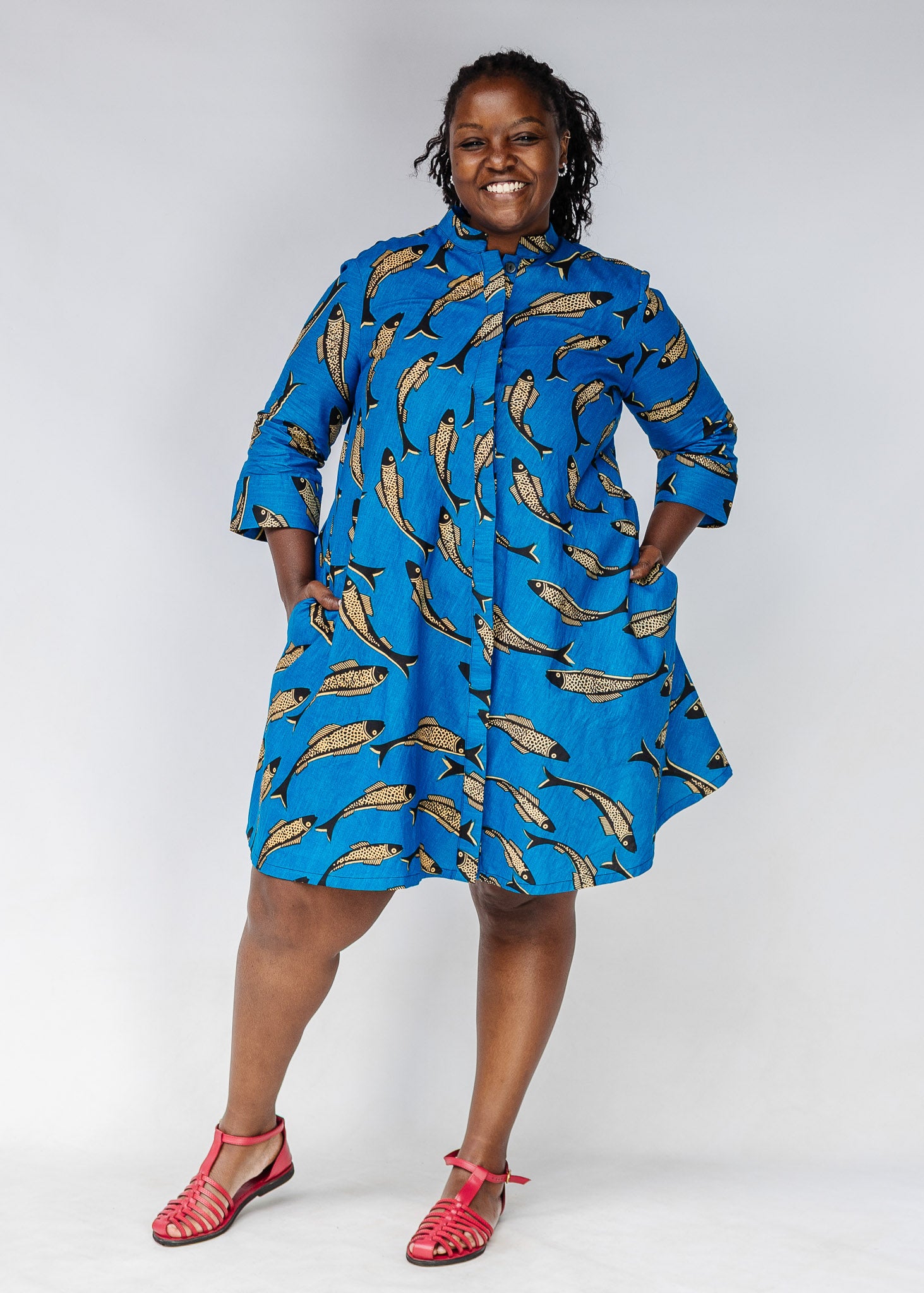 Model wearing blue dress with beige fish print.
