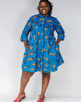 Model wearing blue dress with beige fish print.