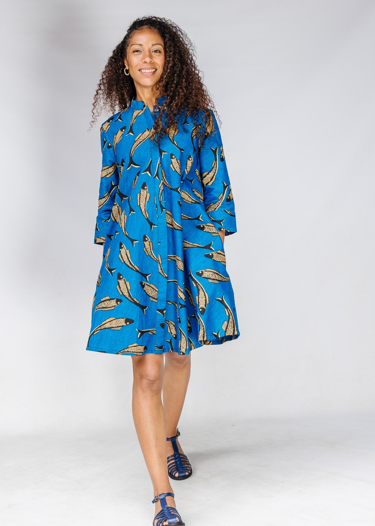 Model wearing blue dress with beige fish print.