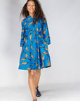 Model wearing blue dress with beige fish print.