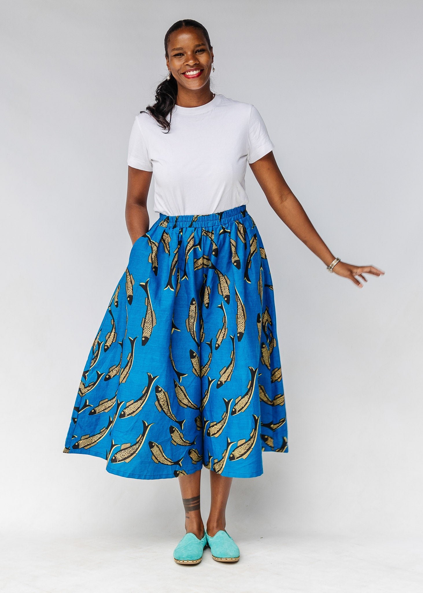 Model wearing white shirt with blue pants with beige fish print.