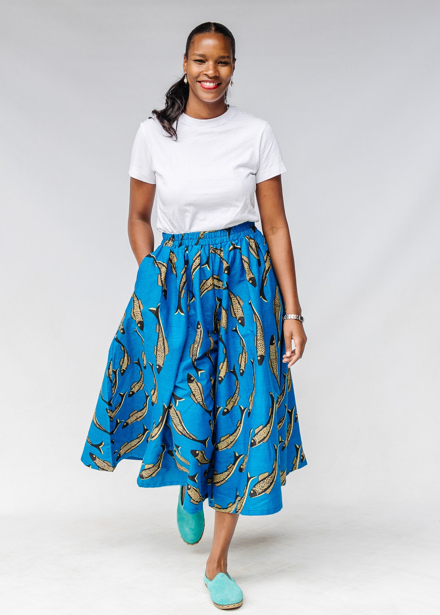 Model wearing white shirt with blue pants with beige fish print.