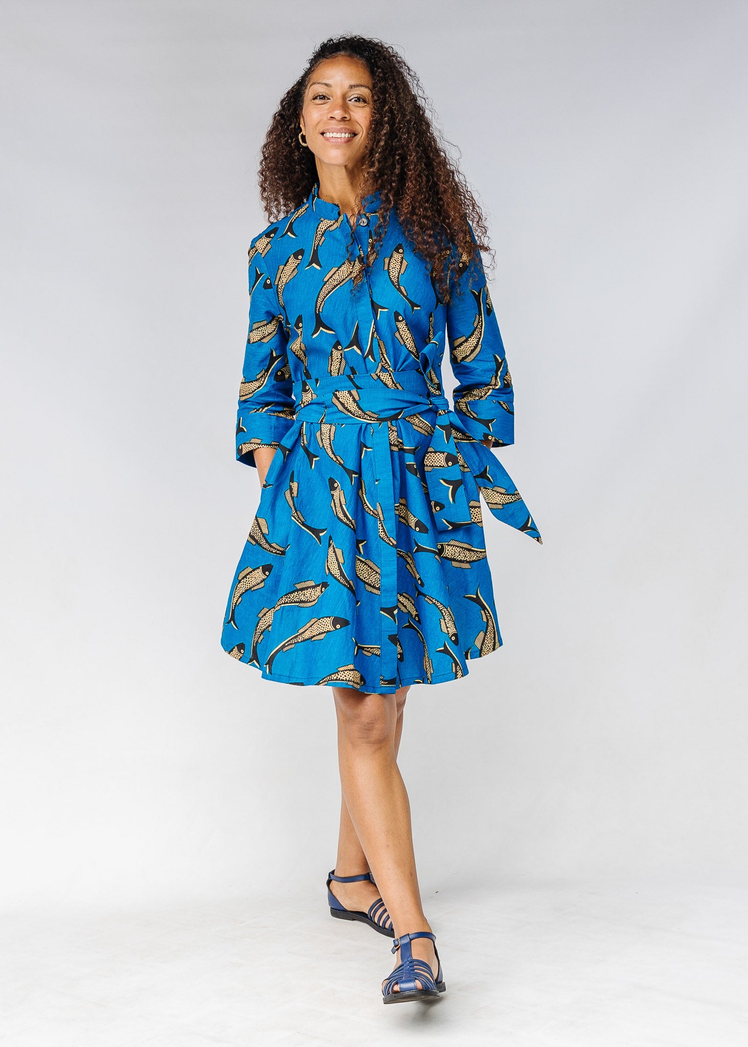 Model wearing blue dress with beige fish print.