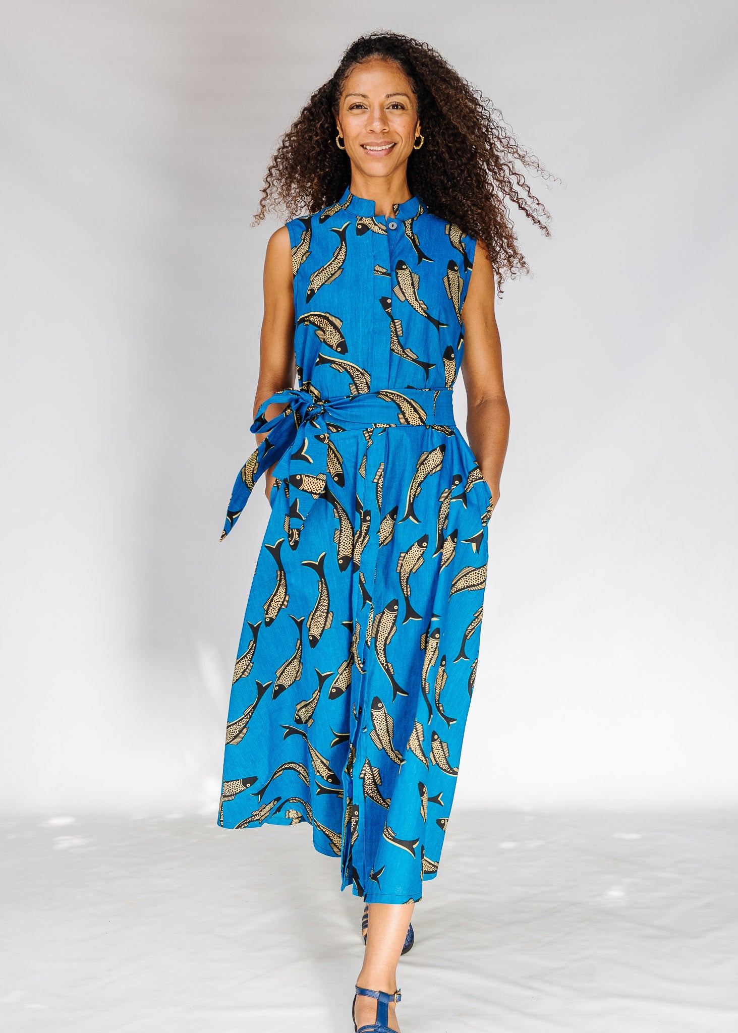 Model wearing blue dress with beige fish print.