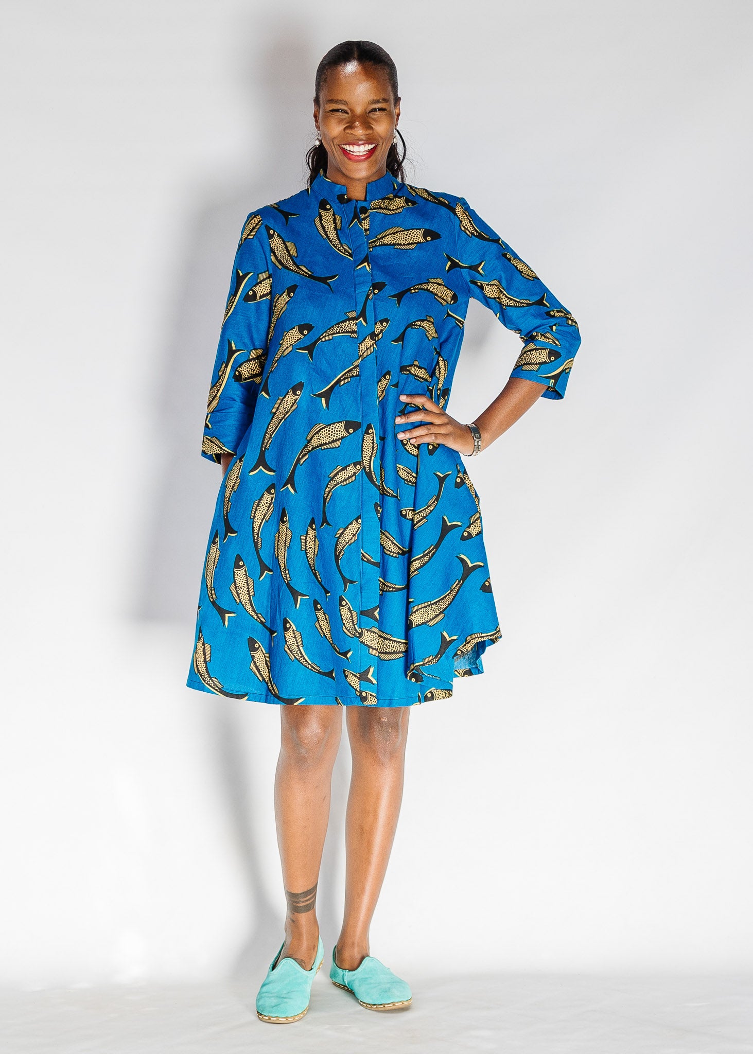 Model wearing blue dress with beige fish print.