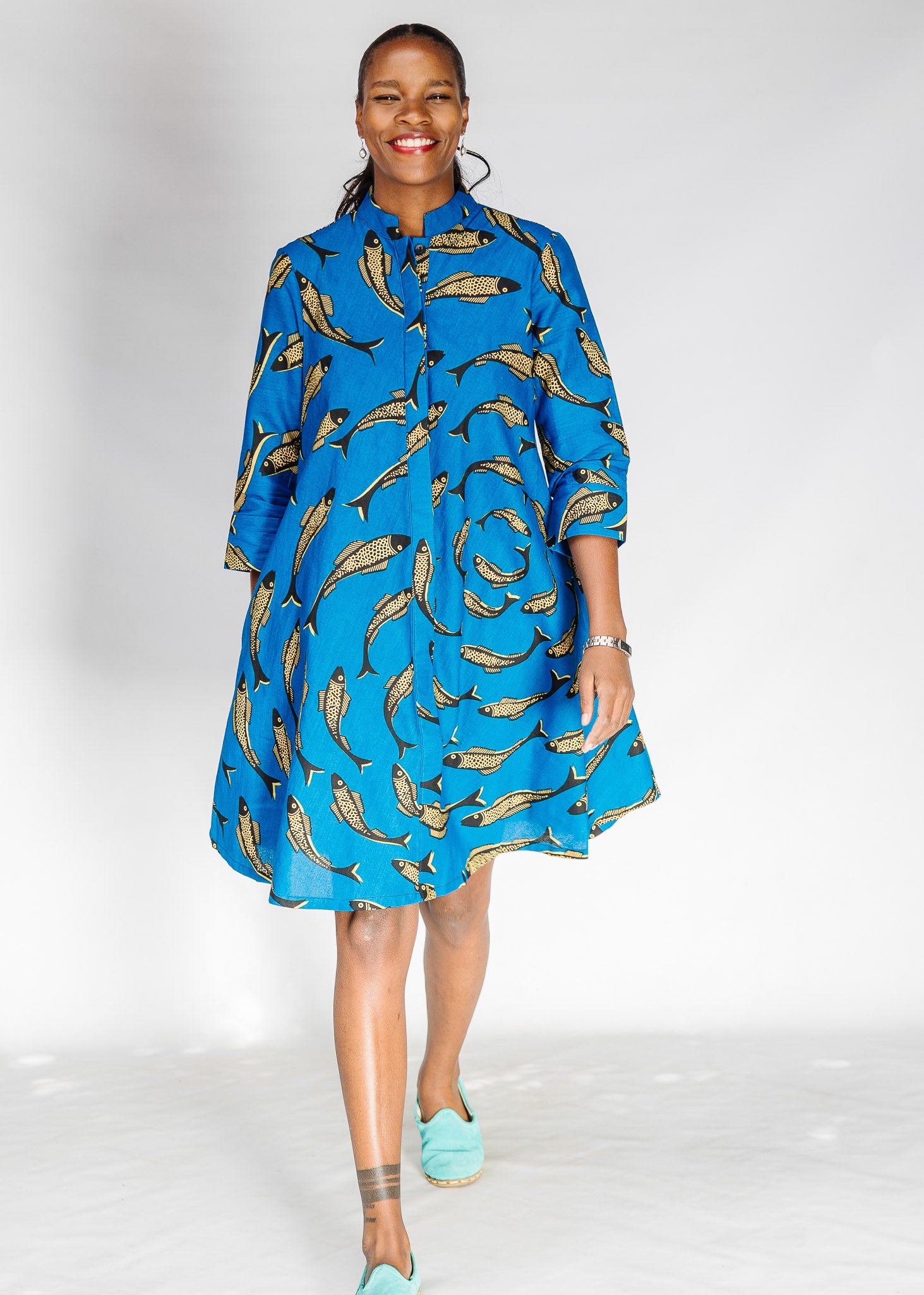 Model wearing blue dress with beige fish print.