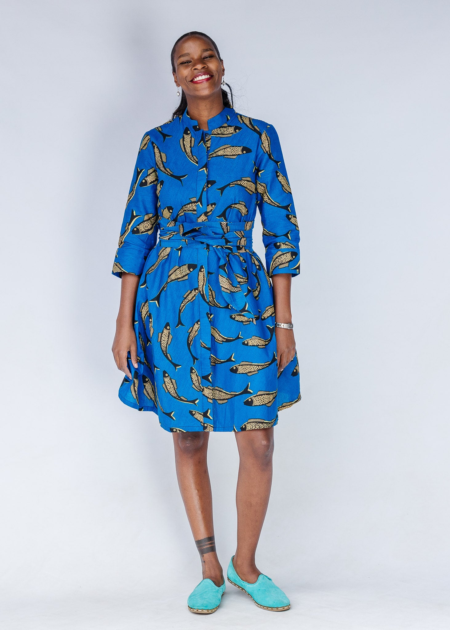Model wearing blue dress with beige fish print.